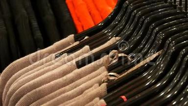 在商场或商场的时装店里，将各种颜色的女士`衣服挂在时尚的黑色衣架上